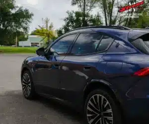 Close-up side view showcasing the dark window tint along the doors and rear window of a dark blue Maserati SUV.