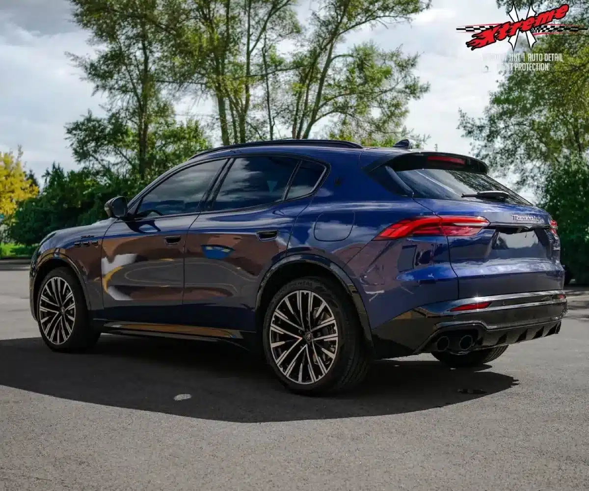 Rear three-quarter view of a metallic dark blue Maserati SUV featuring tinted windows and multi-spoke alloy wheels.